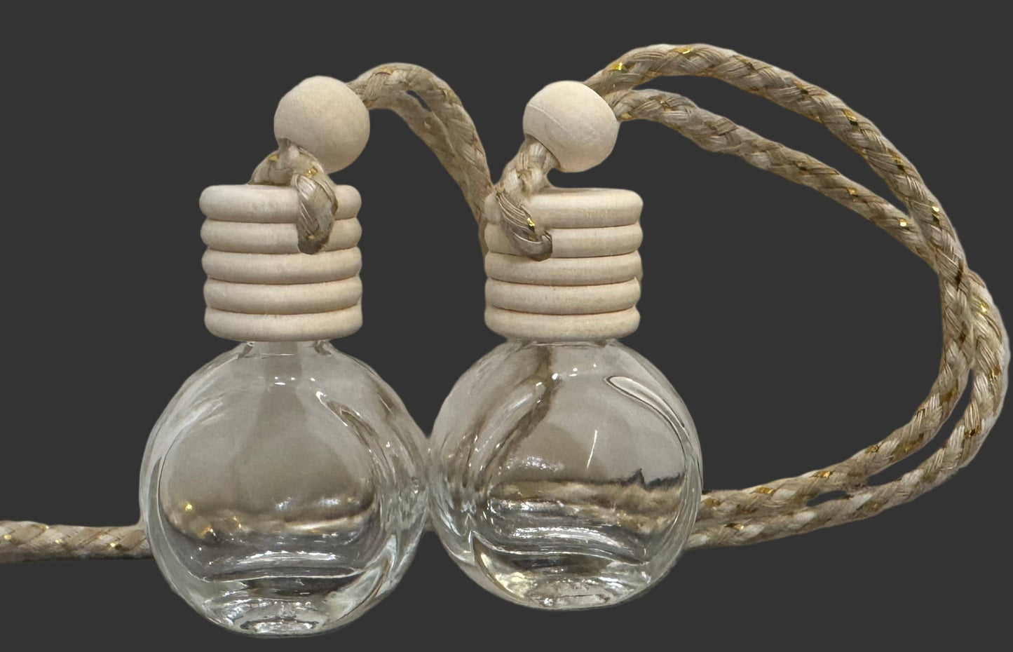 Two clear glass car air freshener
bottles with wooden stoppers and rope on a gray surface.