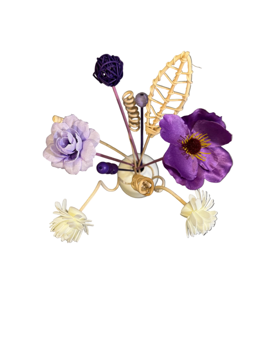 Decorative flower arrangement with a small vase on a reflective surface. Reed diffuser bouquet.