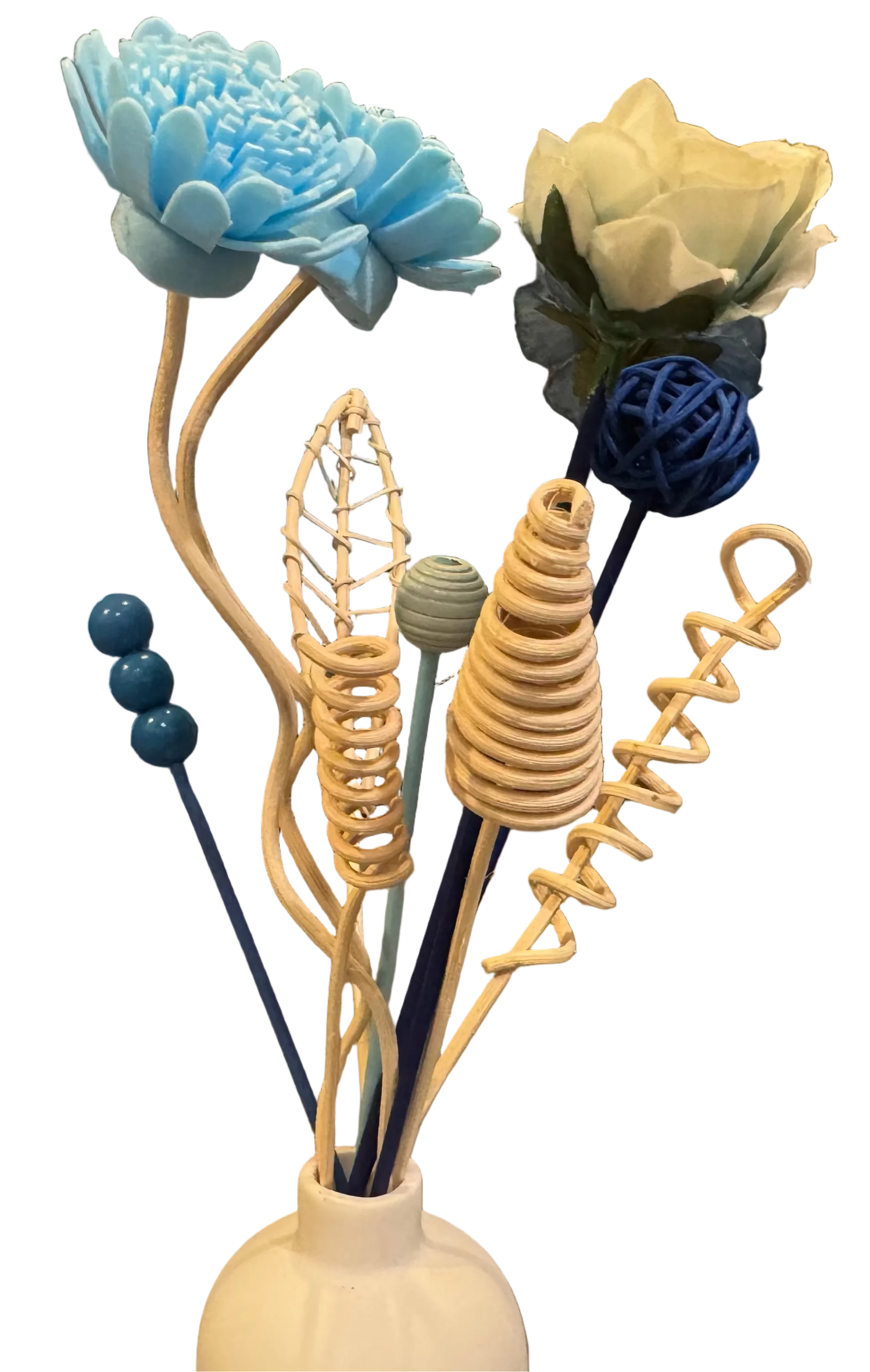 Decorative reed diffuser flower arrangement with blue, white, and beige flowers in a white vase on a table.