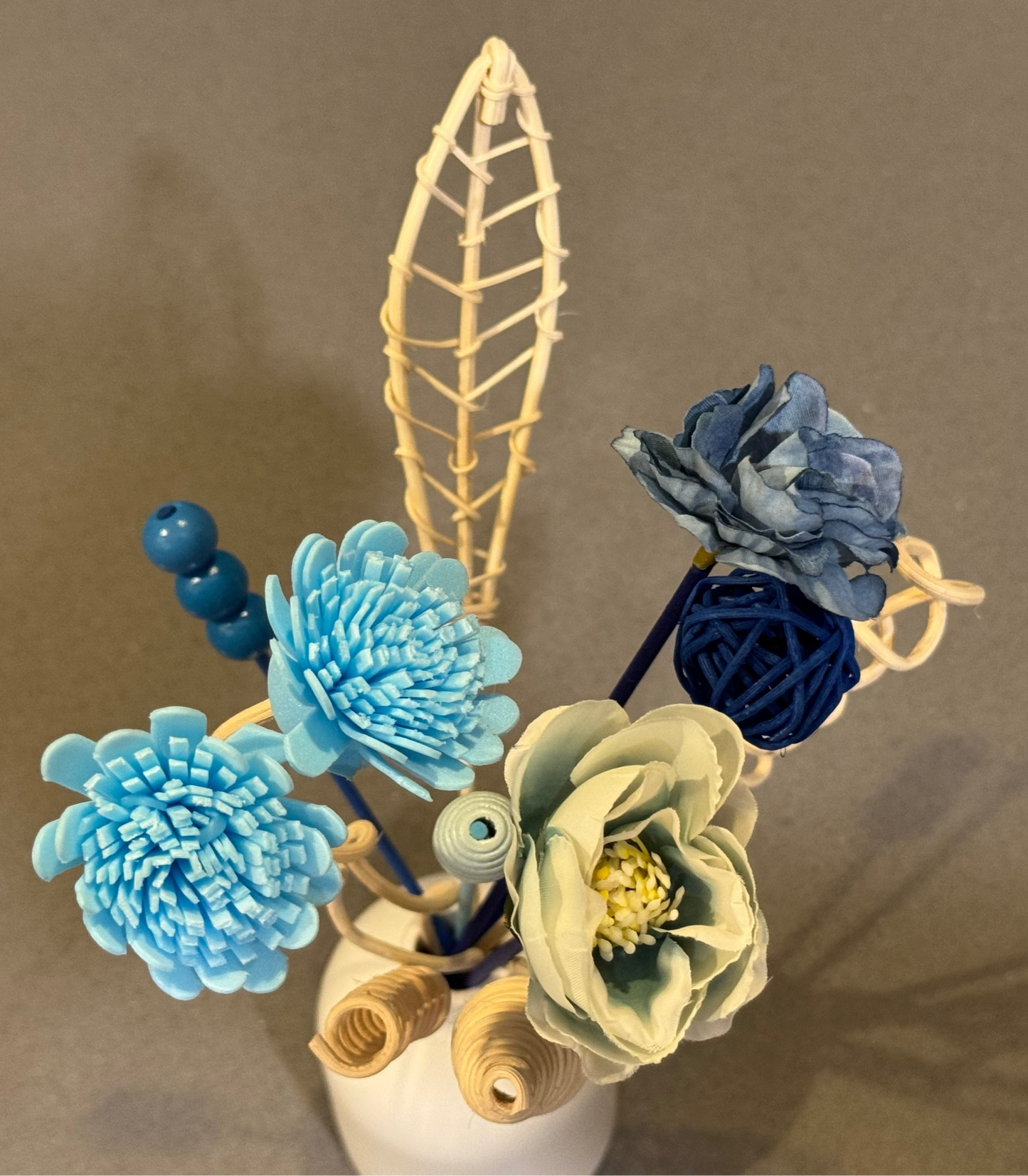 Decorative reed diffuser flower arrangement with blue flowers.