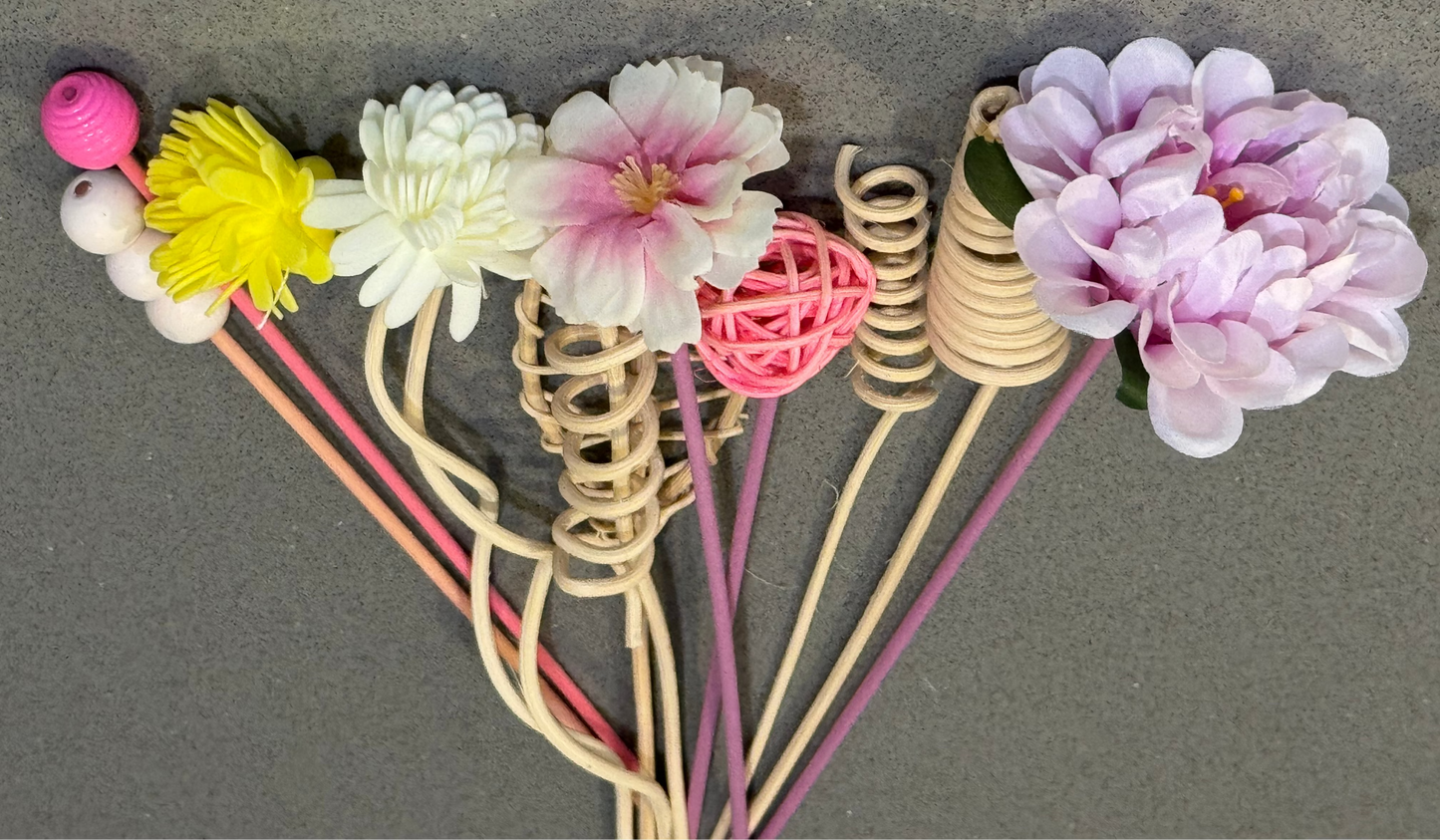 Decorative reed diffusers with floral ends on a gray background