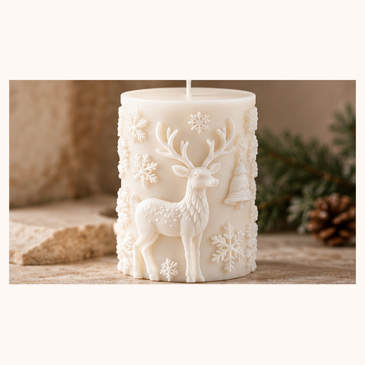 An off-white cylindrical candle with embossed holiday designs, including a deer, snowflakes, and a Christmas tree, set against a rustic background with pine branches and a stone.